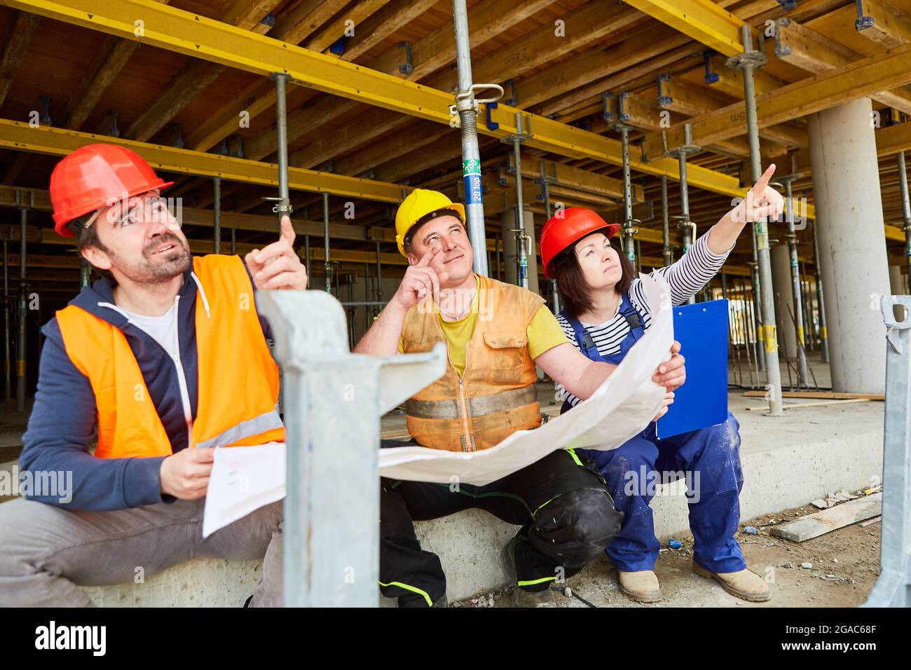 Craftsman and architect as a team with building drawings during the planning on the construction site in the shell Stock Photo