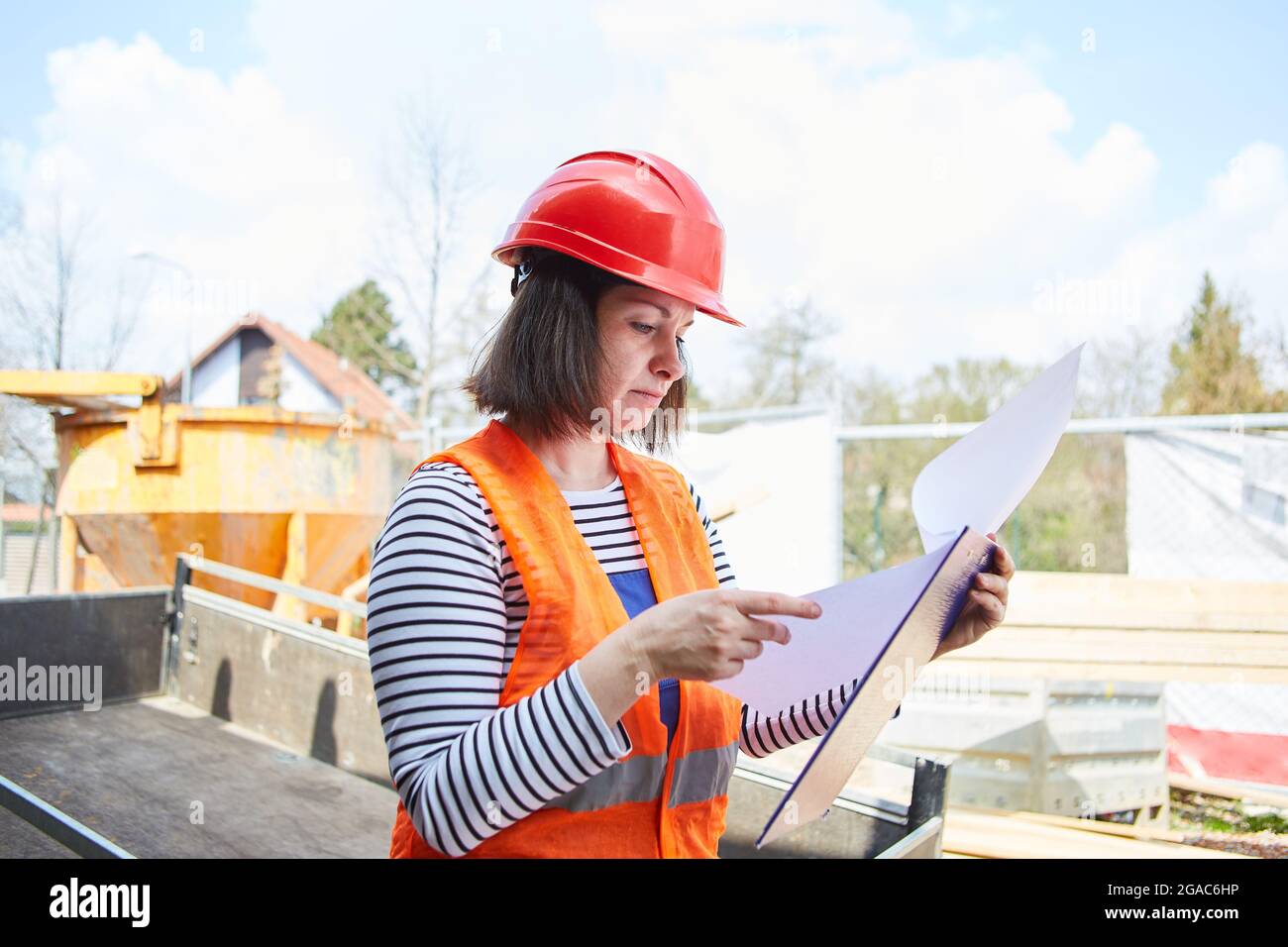 Architect with protective helmet on the construction site for building a house controls the construction project with a checklist Stock Photo