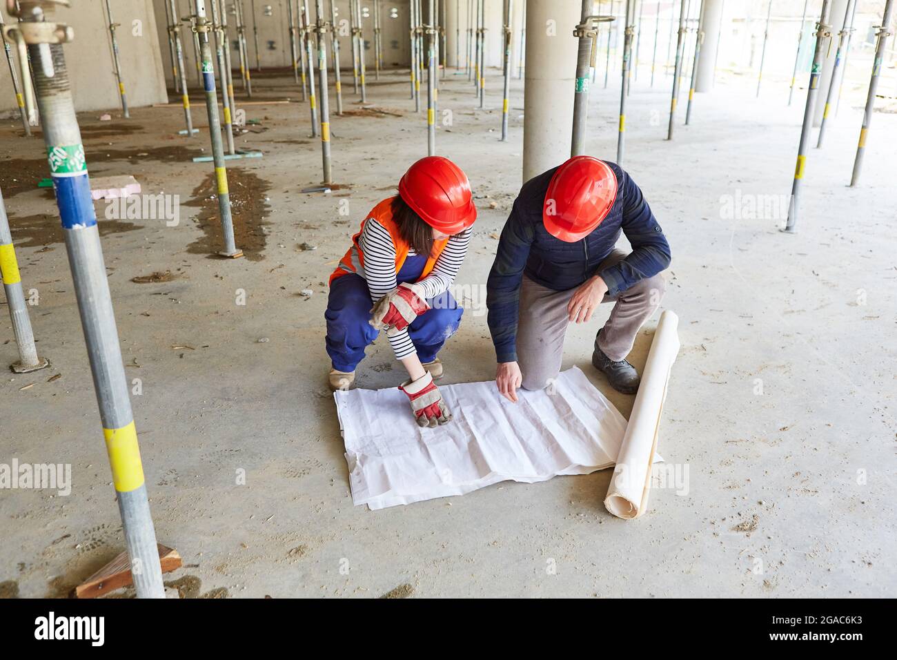 Architect and construction worker with blueprint in the shell of the construction site when planning the renovation Stock Photo