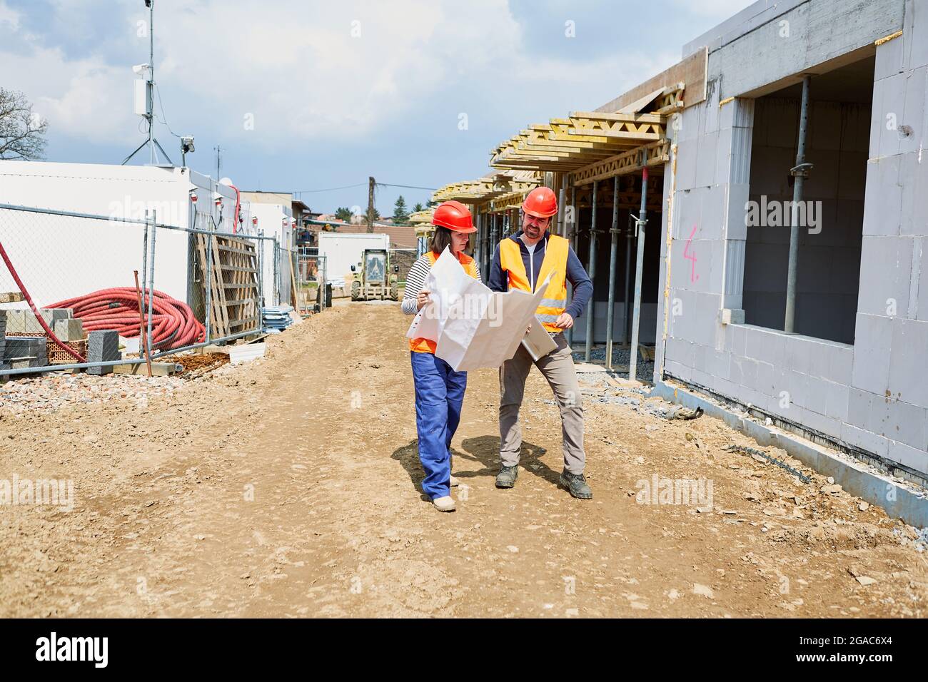 Craftsman and architect with construction drawing discuss the construction project before the shell of a construction site Stock Photo