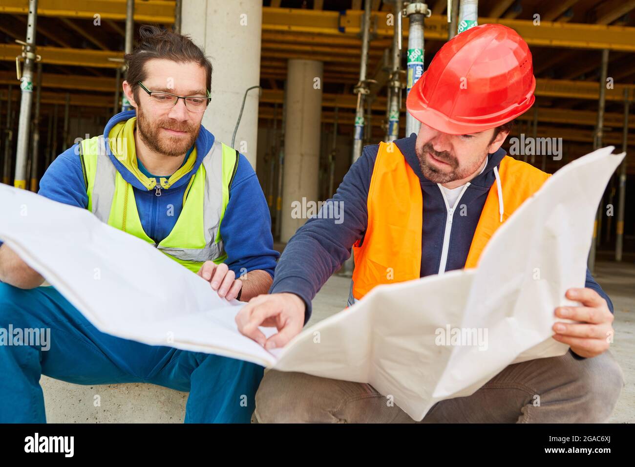 Architect with construction plan gives craftsmen as foreman instructions on the construction site for building the house Stock Photo