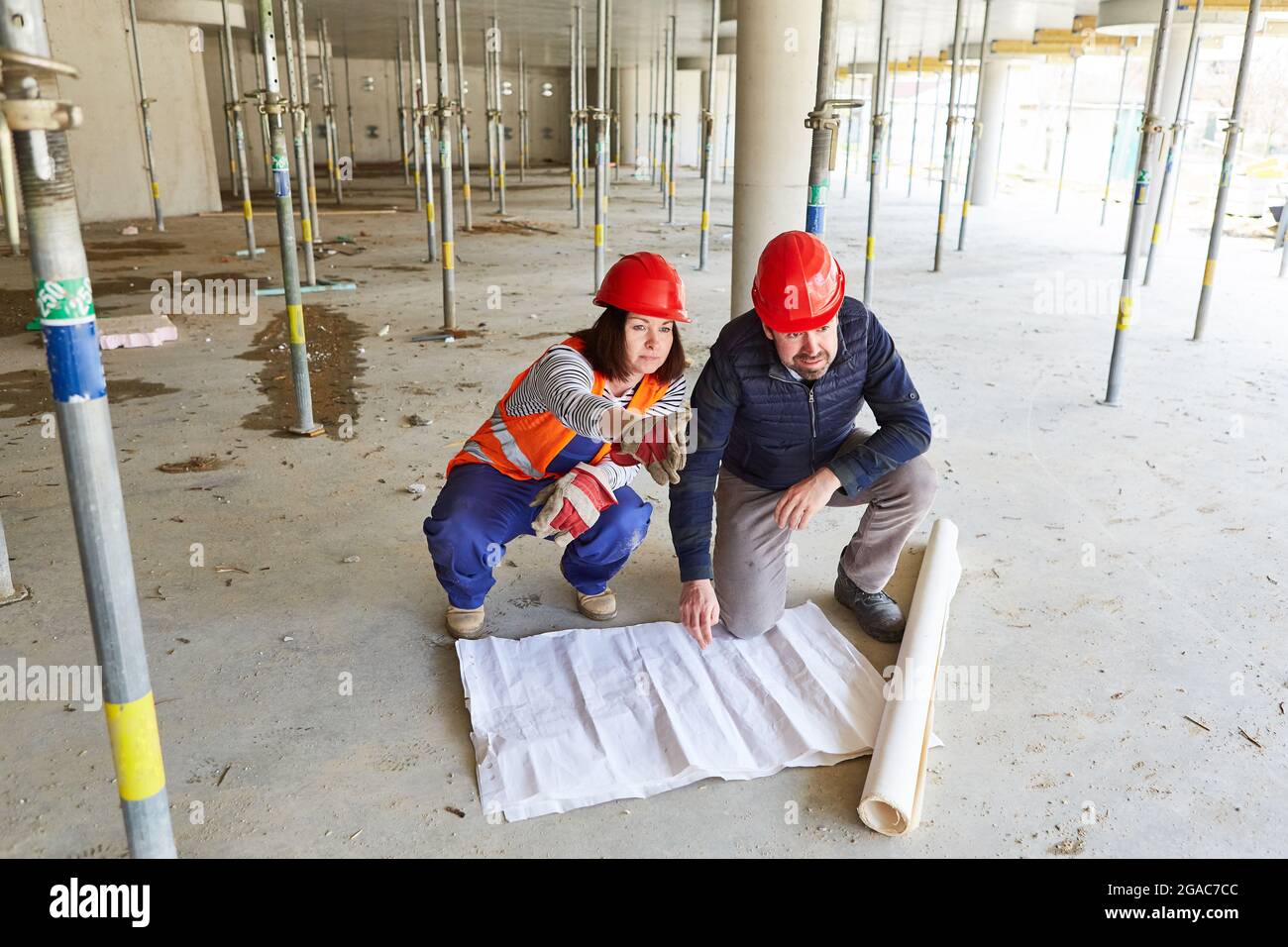 Worker and architect together in the shell of a building project when coordinating with the building drawing Stock Photo