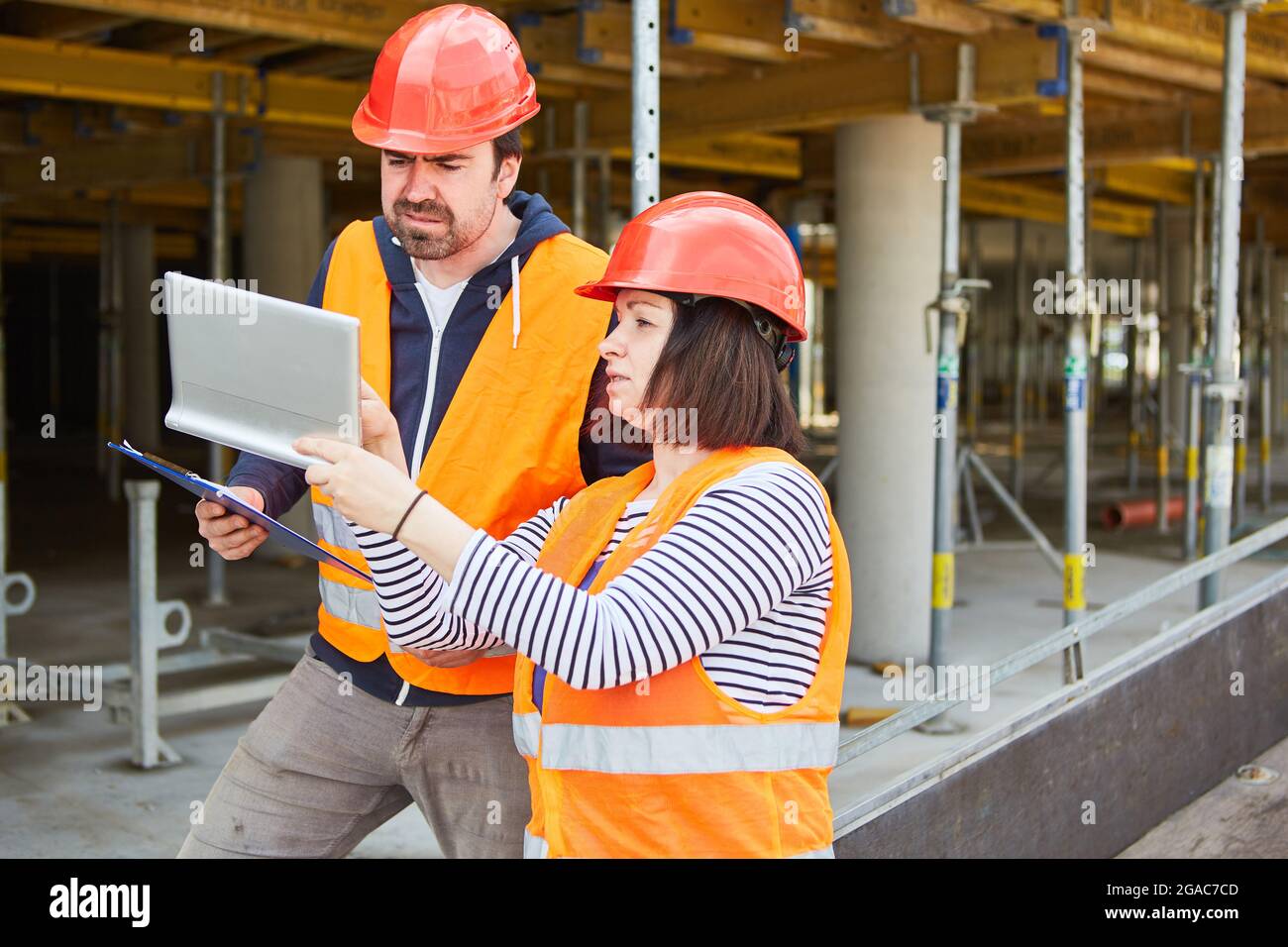 Foreman and architect with tablet computer discuss construction planning on construction site in the shell Stock Photo