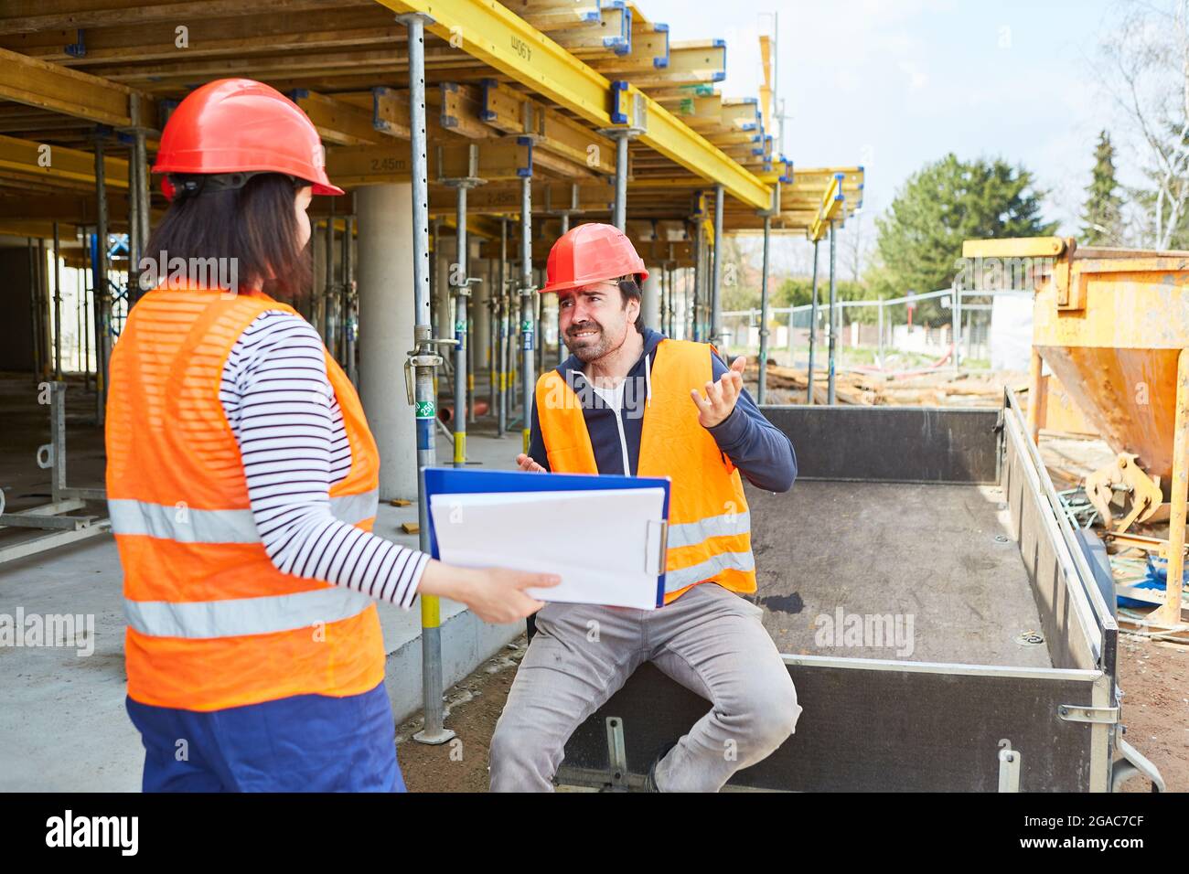 The architect and construction worker discuss the construction project together on the shell of the construction site Stock Photo