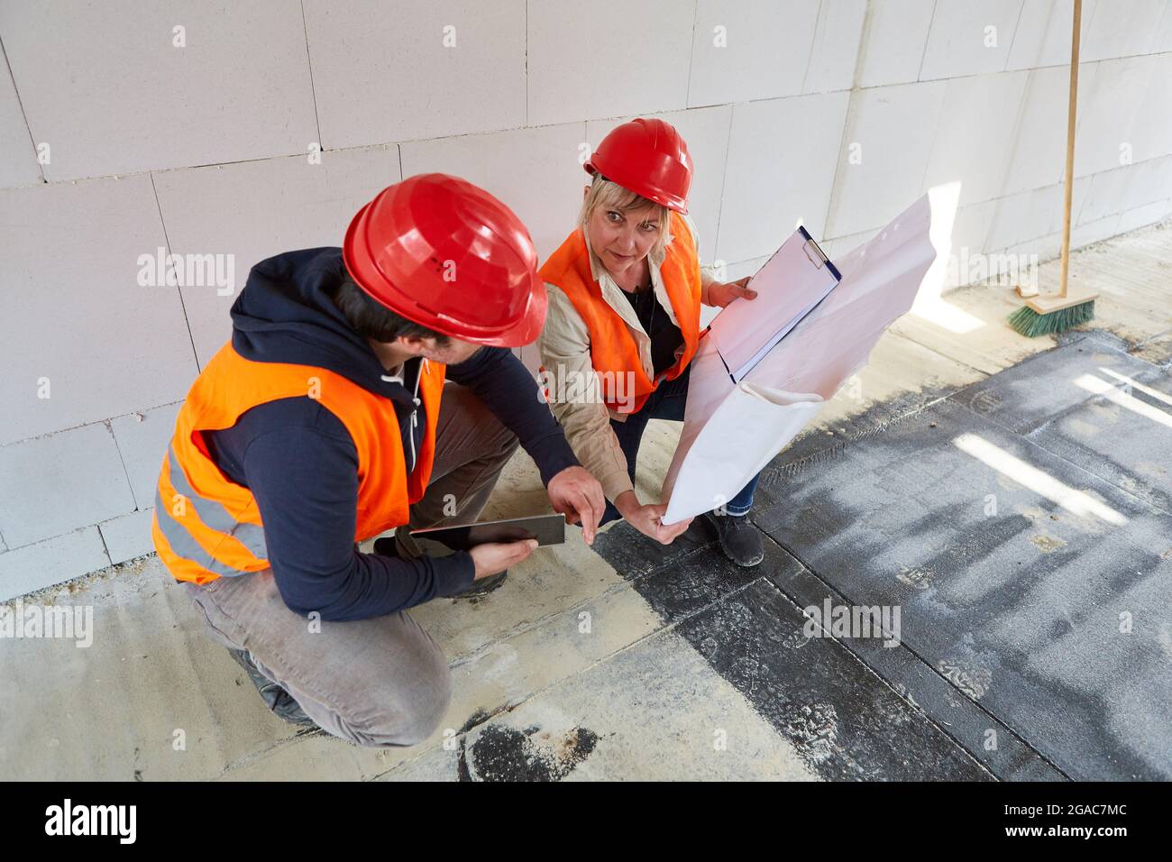 Foreman and architect with floor plan plan the construction project together in the shell of the construction site Stock Photo