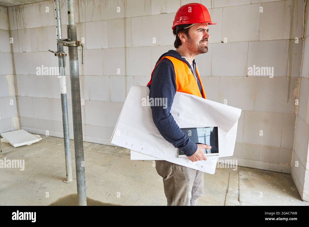 An architect or building expert with a construction plan critically checks the shell of a construction site Stock Photo