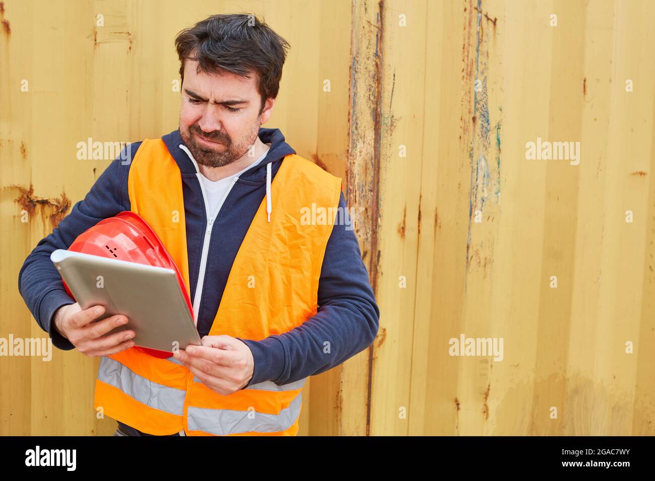 Construction worker as foreman looks critically at the tablet computer during construction planning online Stock Photo