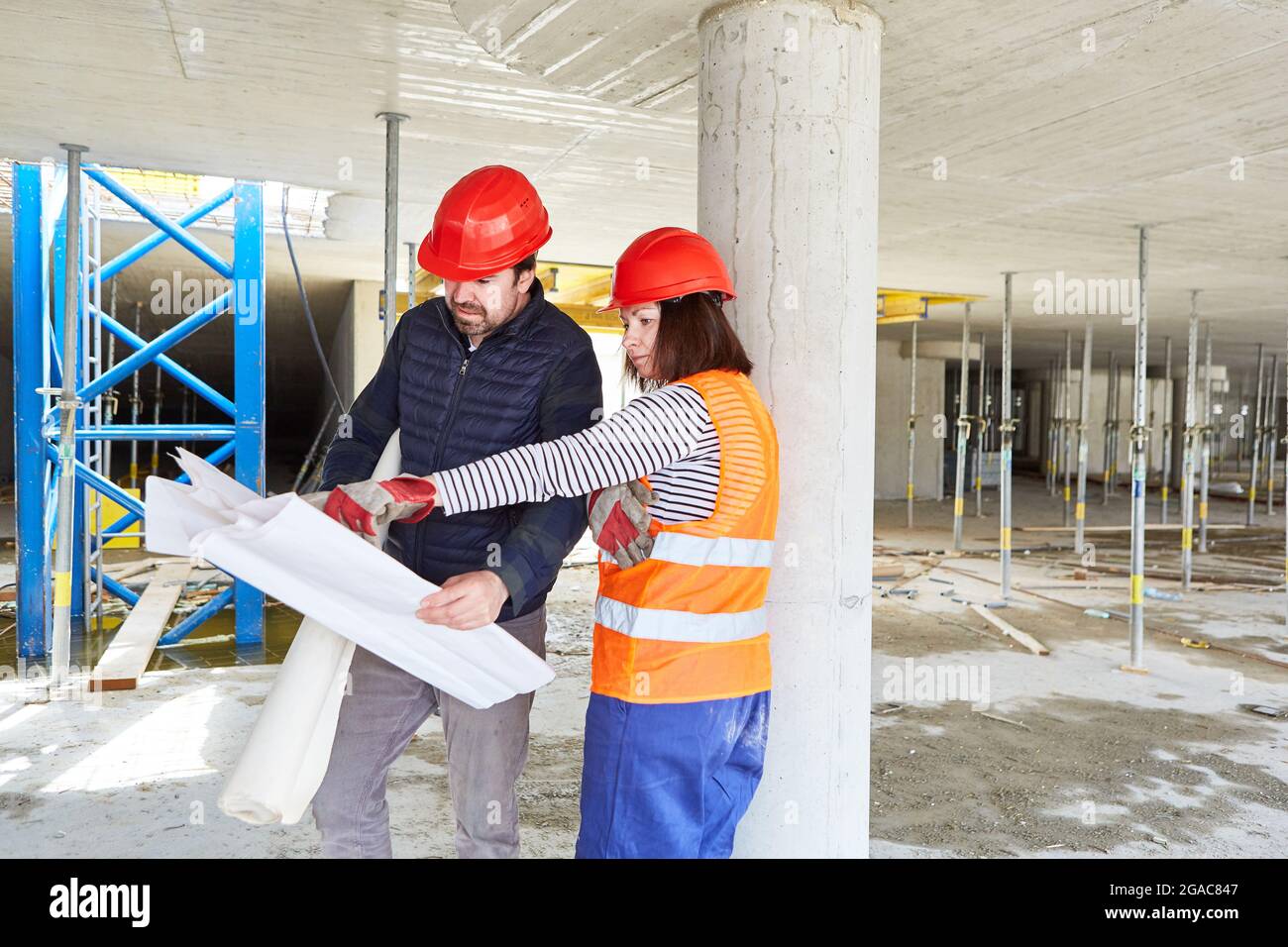 Foreman and architect with construction drawing discuss the building project on the construction site in the shell Stock Photo
