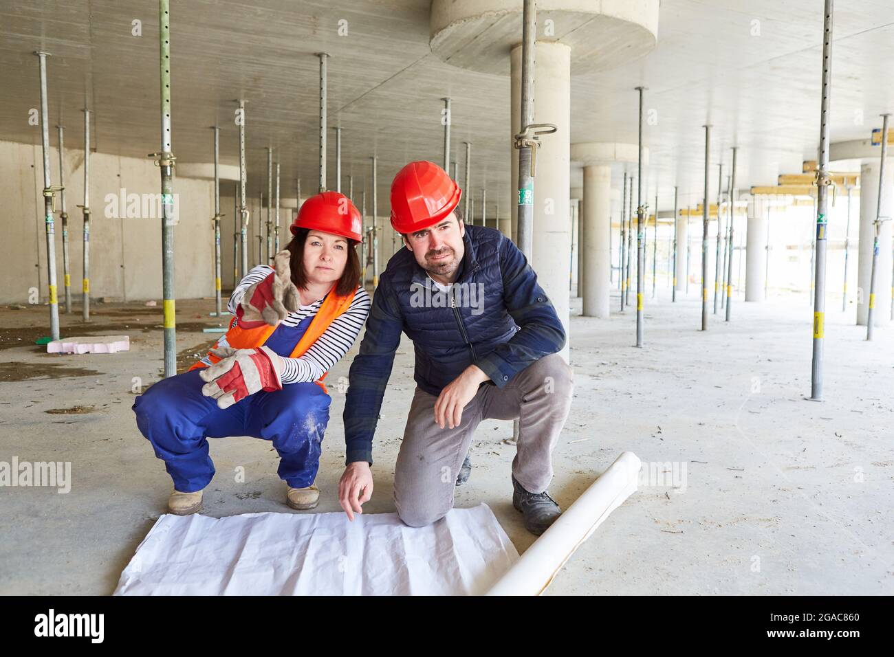 Worker and architect with floor plan together on a construction site in the shell of a construction site Stock Photo