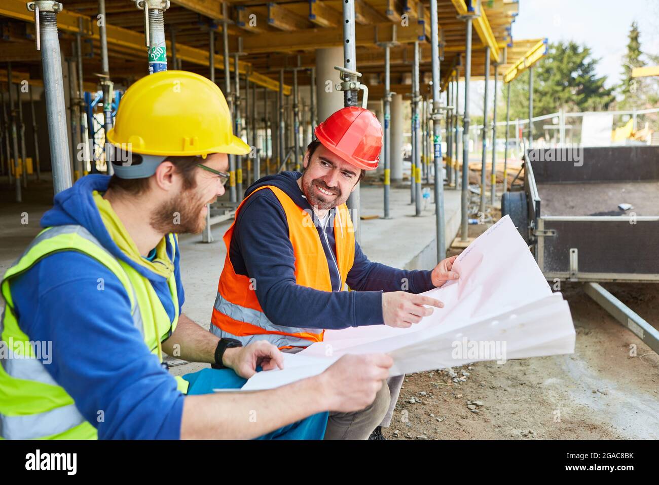 Architect with construction drawing discusses the construction planning with the foreman on the new construction site Stock Photo