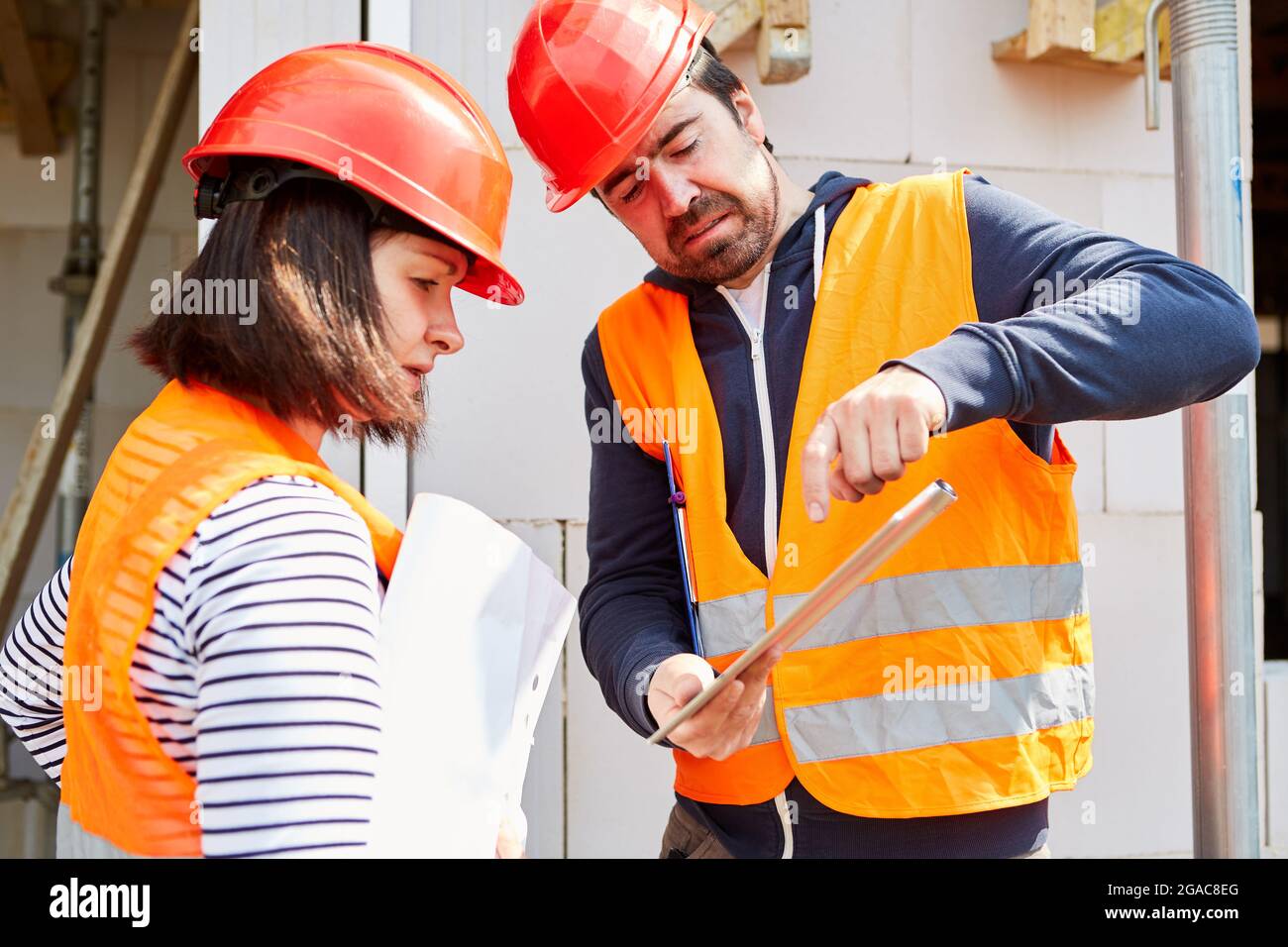 Architect and foreman with tablet computer discussing construction project at the construction site Stock Photo