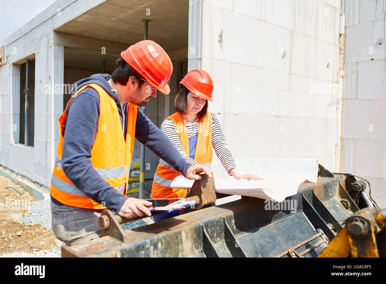 Construction workers and architect with floor plan discuss construction project on a construction site in the shell Stock Photo