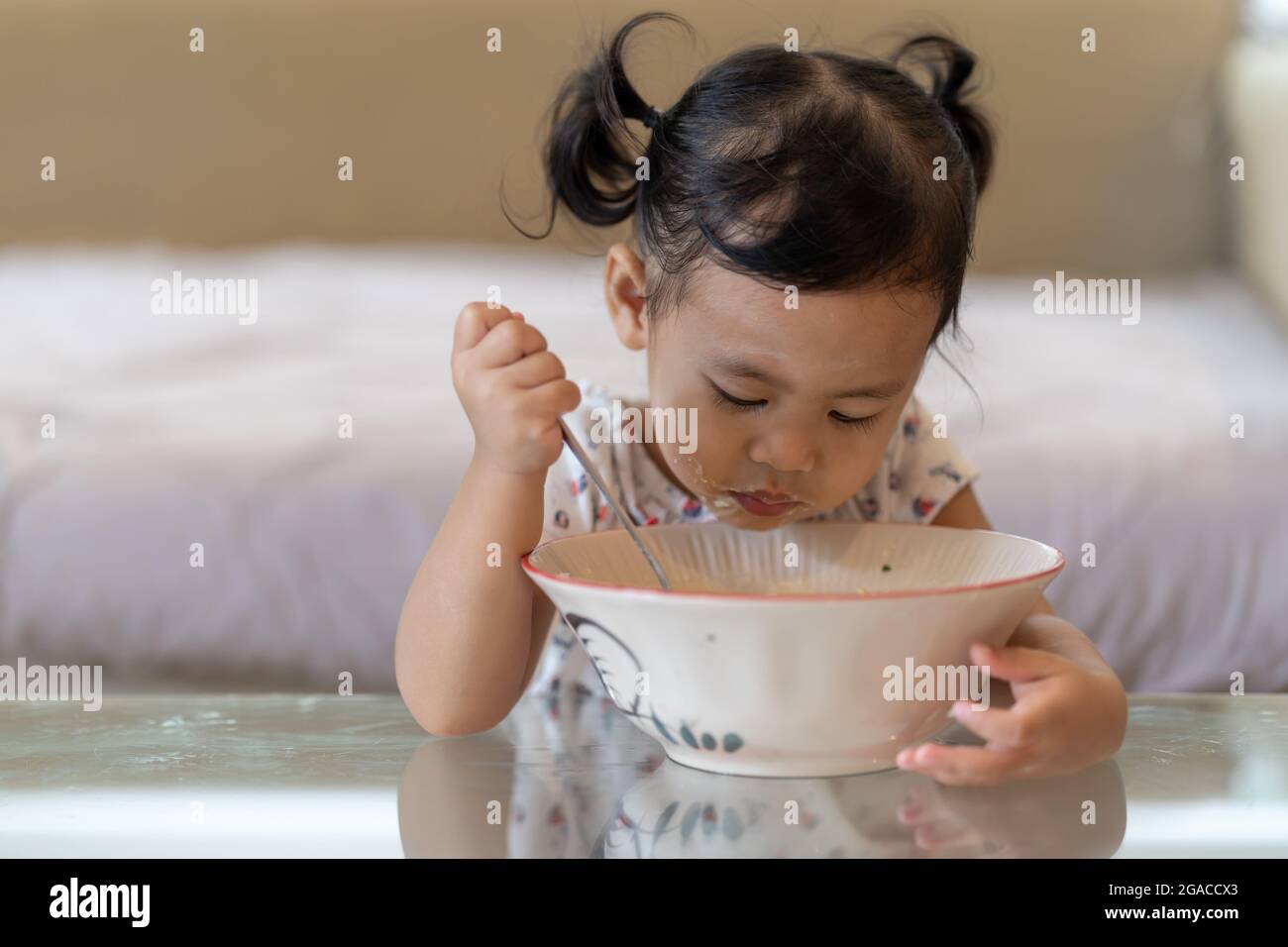 Little Thai girl eating from a big bowl Stock Photo