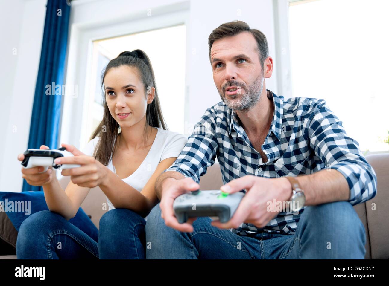 Couple playing computer games, playing the console, holding pads in their hands Stock Photo