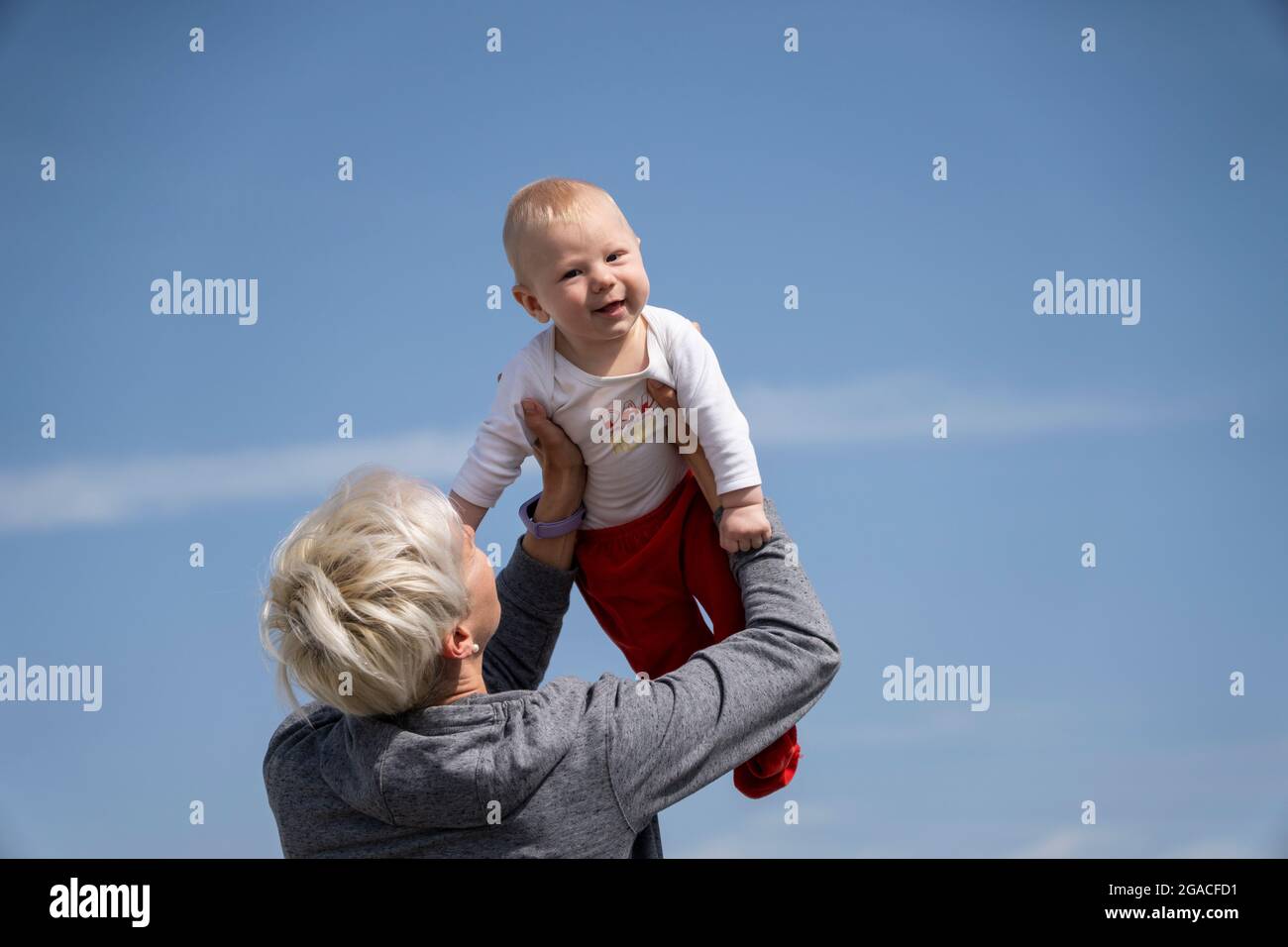Mother holding his small baby son against blue sky Stock Photo