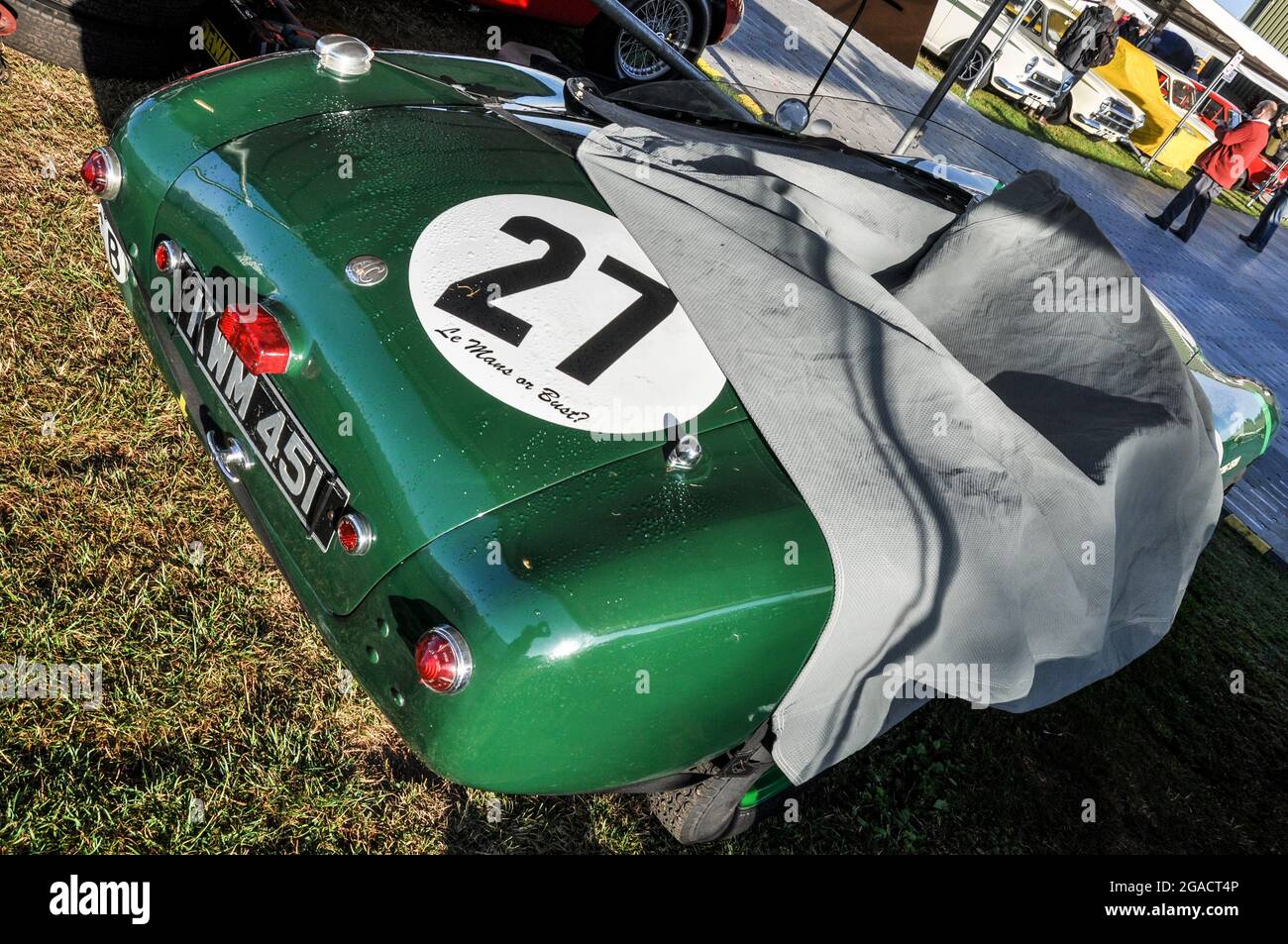 Le Mans or Bust slogan on green AC classic motor racing car. Cover partially removed. Goodwood Revival. AC Cars Ltd. Dust sheet. Number 27 Stock Photo