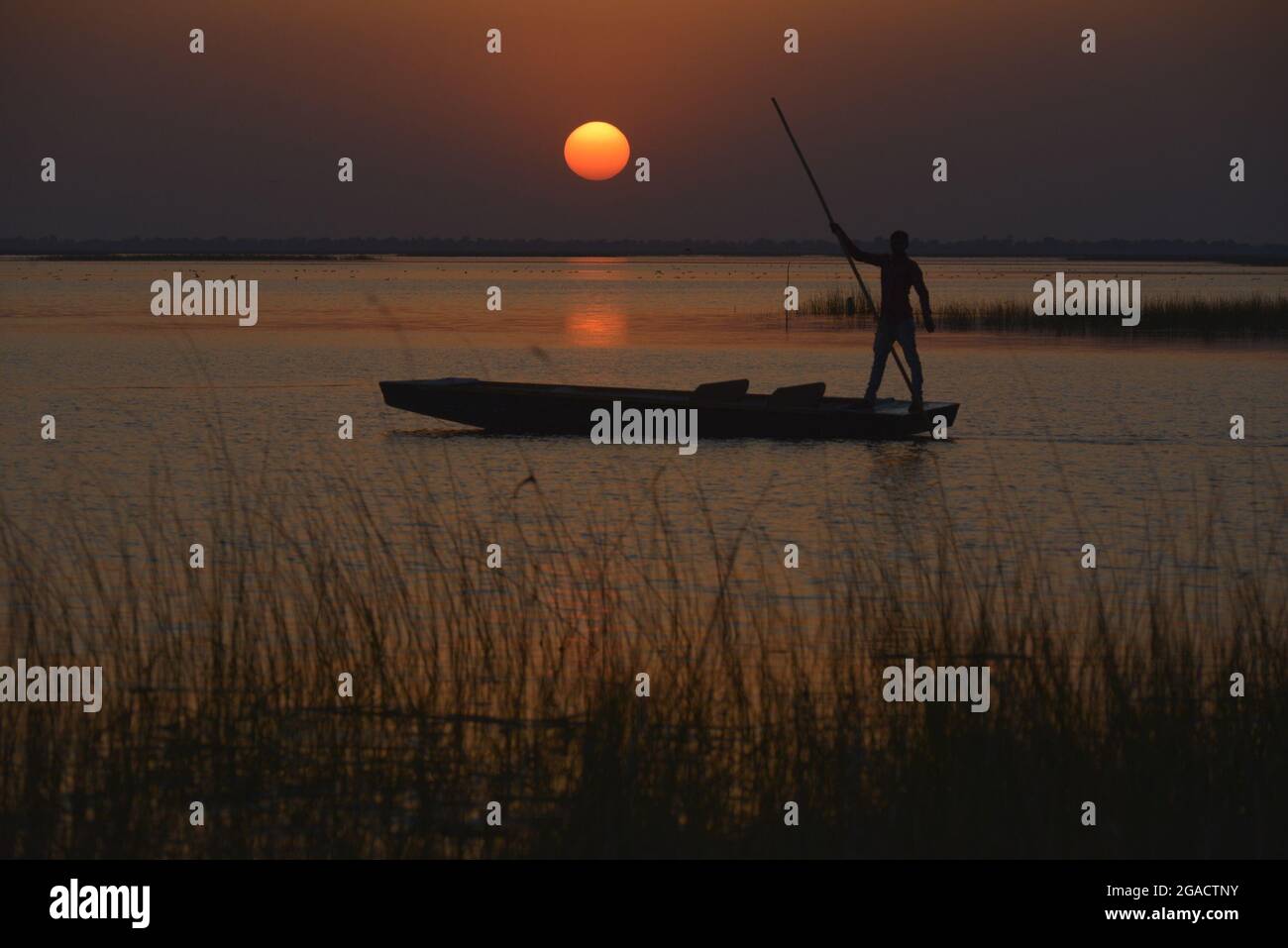 Fisherman silhouette in a boat during sunset Stock Photo - Alamy