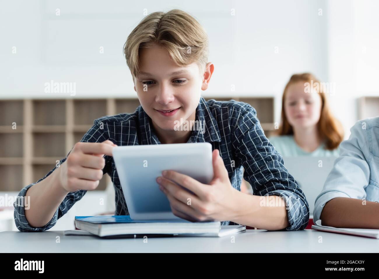 Smiling schoolboy using digital tablet near notebook Stock Photo