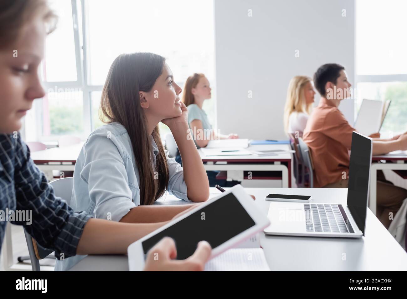 blurred boy using digital tablet near classmates during lesson Stock Photo