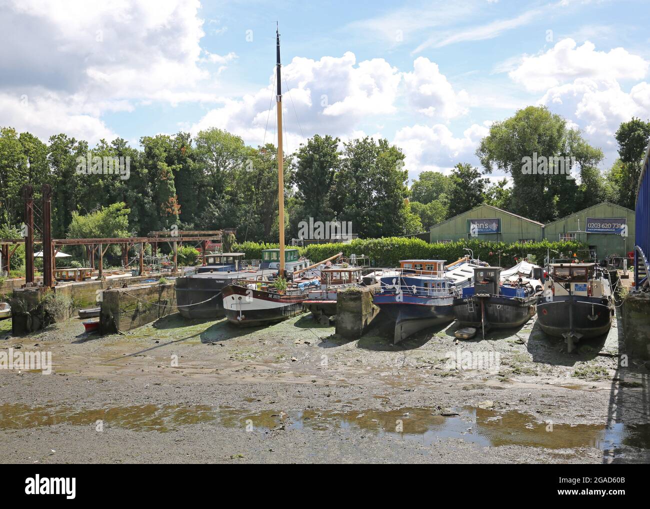 Houseboats sit on river mud at low tide at Johns Boatworks on Lots Ait - an island in the River Thames at Brentford, west London, UK Stock Photo