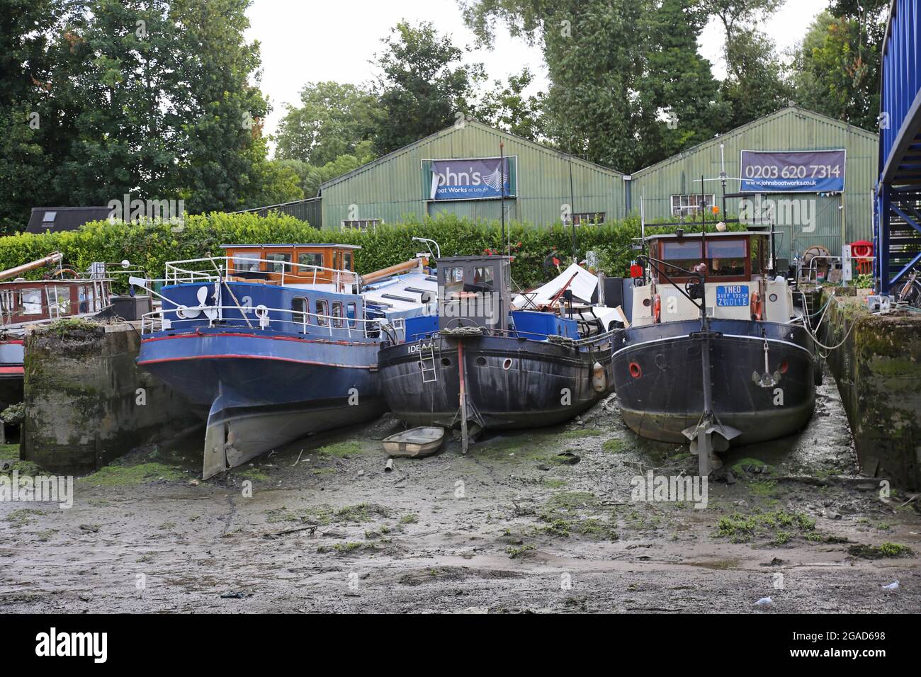 Houseboats sit on river mud at low tide at Johns Boatworks on Lots Ait - an island in the River Thames at Brentford, west London, UK Stock Photo