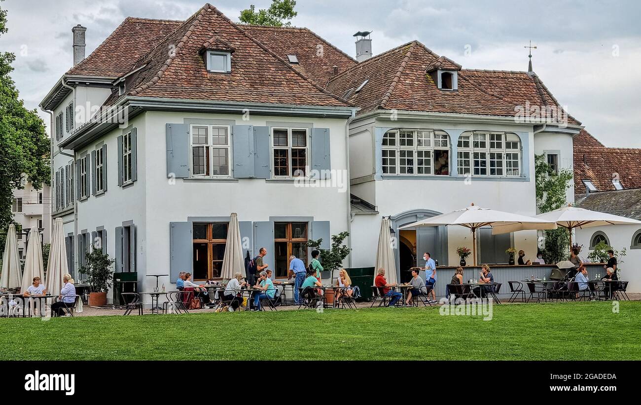 Fondation Beyeler garden cafe building coffee house with people sitting under white umbrellas in the park near the museum. Stock Photo