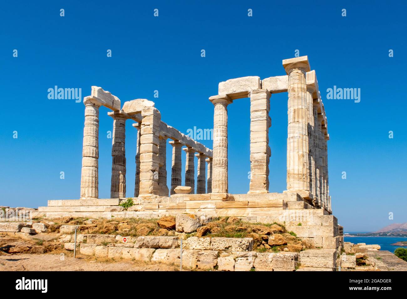 The ancient Greek Temple of Poseidon at Cape Sounion, doric columns and ruins on the hill with crystal blue sky background. Stock Photo