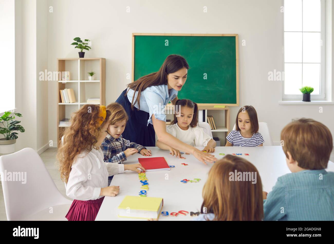 Portrait of diligent schoolkids and teacher studying talking at lesson Stock Photo