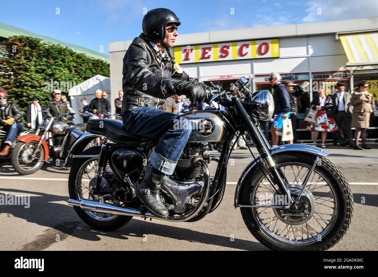 Period motorcyclist in retro biker gear at the Goodwood Revival outside the retro Tesco shop, store. Vintage, classic, timeless. Step back in time Stock Photo