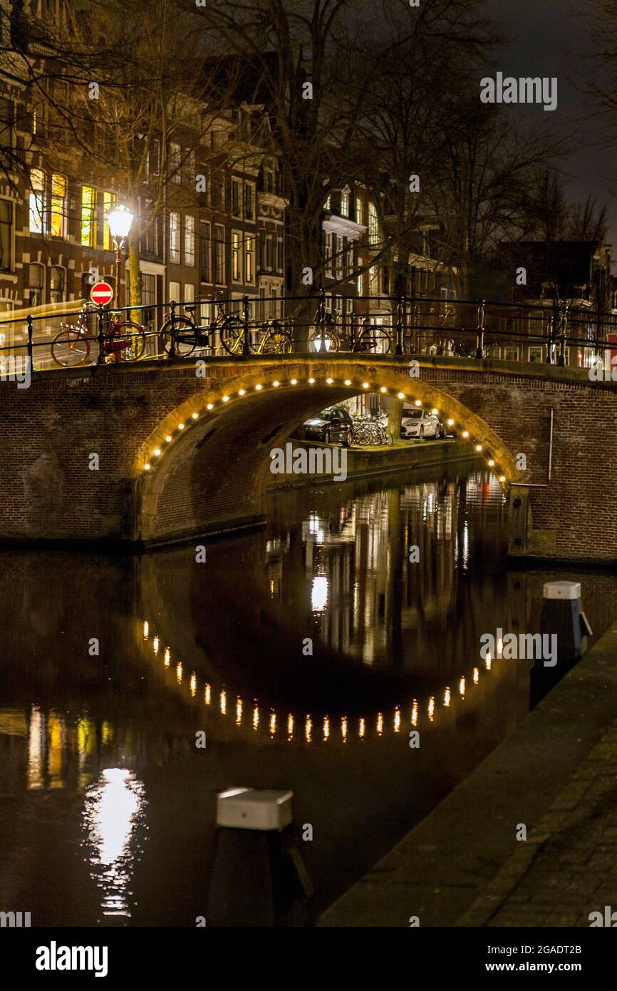 Illuminated arched canal bridge at the junction of Kerkstraat and Reguliersgracht, Amsterdam, the Netherlands Stock Photo