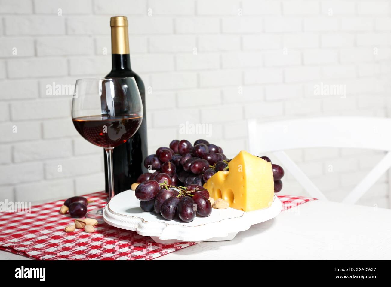 Red grape and cheese with glass bottle of wine on light interior