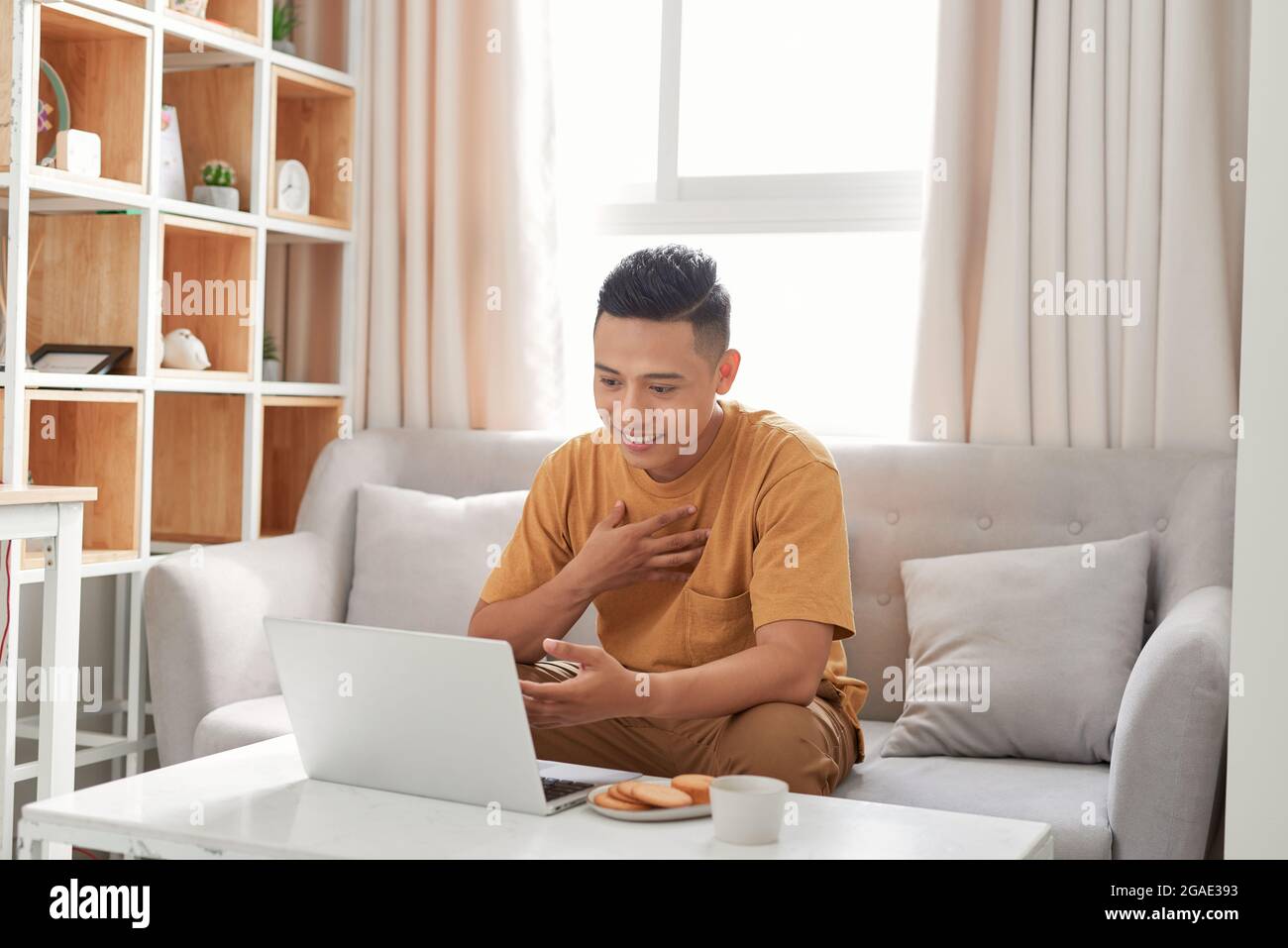 Remote job. Young handsome man making video call with friends while sitting on sofa at his modern home Stock Photo