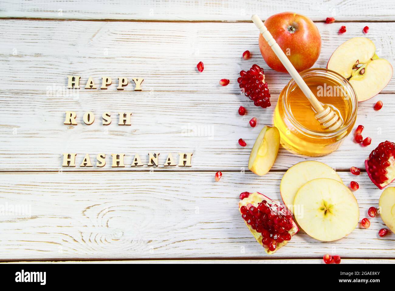 Happy Rosh Hashanah. Inscription on a wooden background. Traditional symbols of celebration. Apples, pomegranates and honey. Stock Photo