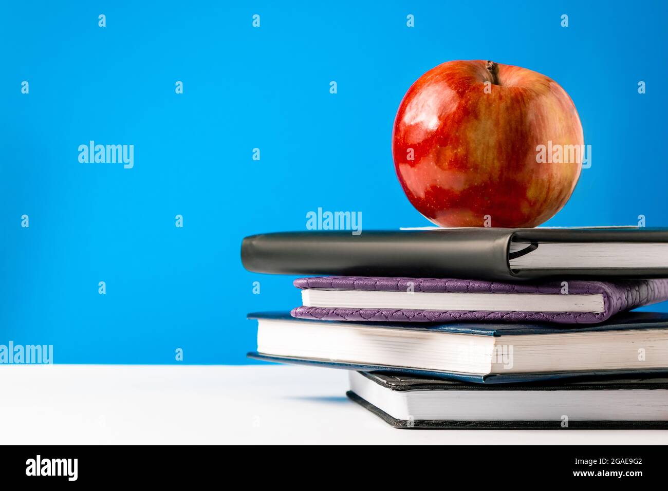 Back to school concept. A stack of books and an apple on a blue ...