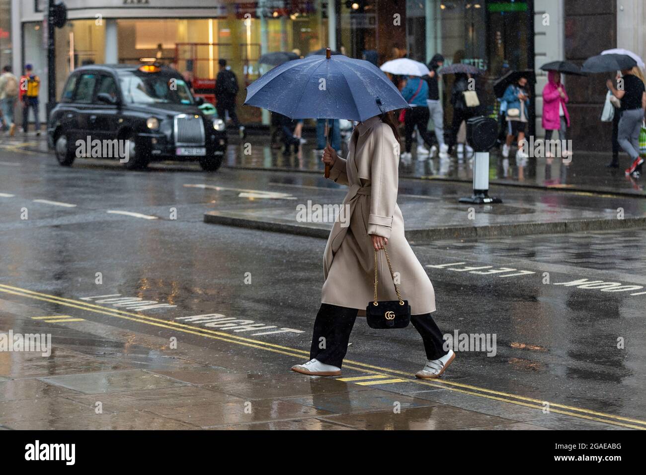 London, UK. 30 July 2021. UK Weather - People in Oxford Street experience windy and rainy conditions as Storm Evert passes across the capital. Yellow warnings for wind and thunderstorms are in place across the east and south-east of England.  Credit: Stephen Chung / Alamy Live News Stock Photo