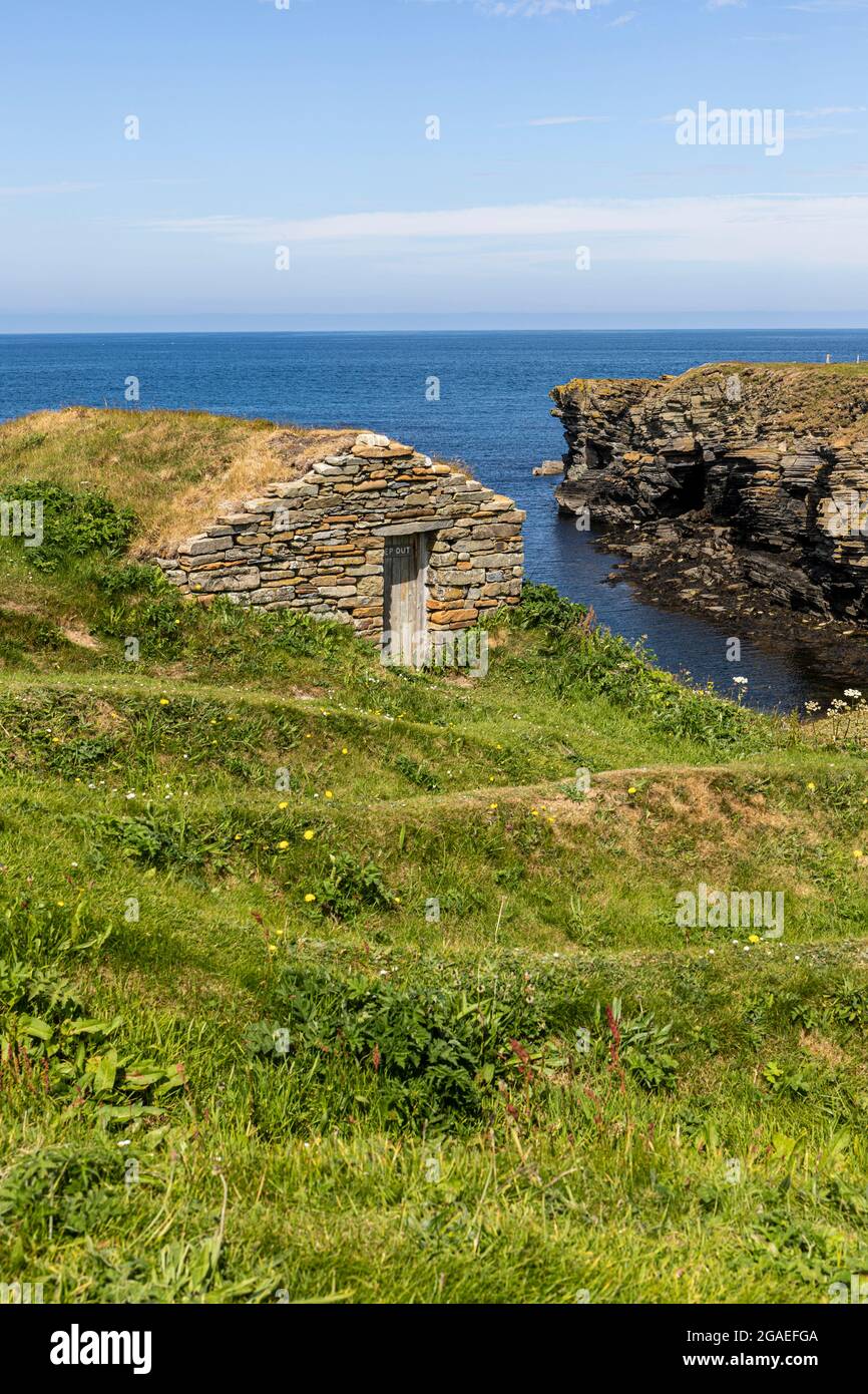 Restored ancient, possibly Viking, harbour with protective cut outs called  'nousts' or 'noasts' for boats laid up ashore and fisherman's hut Stock Photo