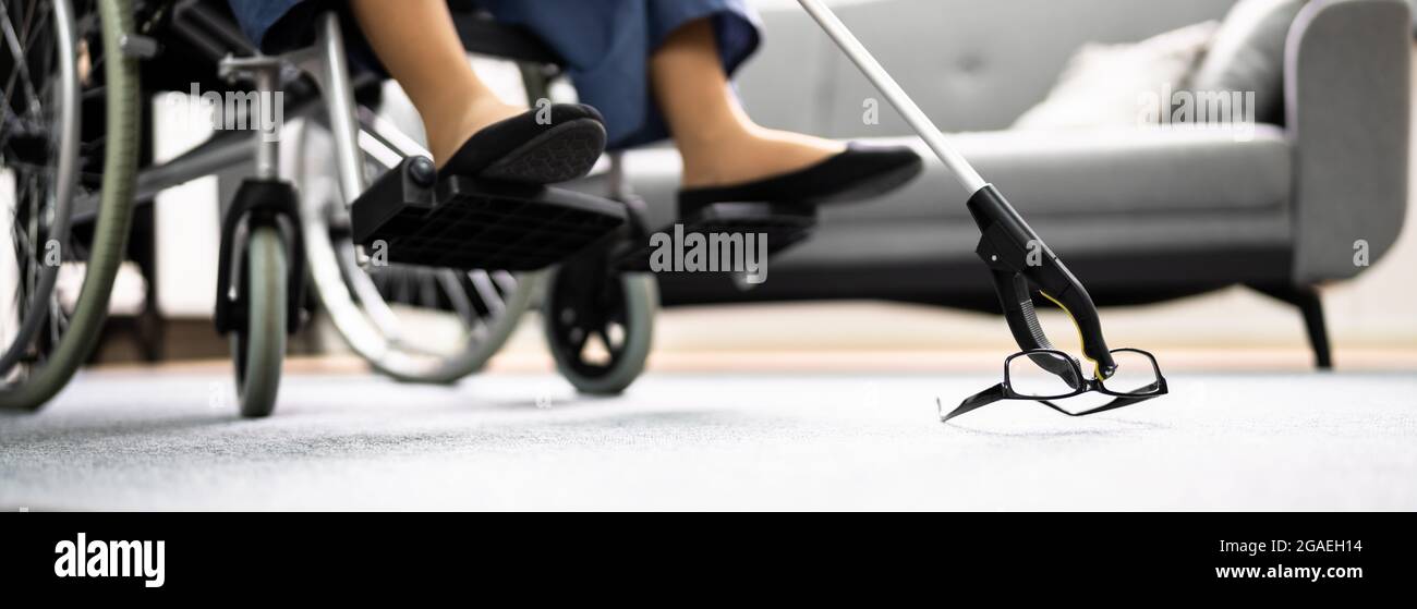 Disabled Woman In Wheelchair Using Grabber Tool Or Reacher For Fallen Glasses Stock Photo