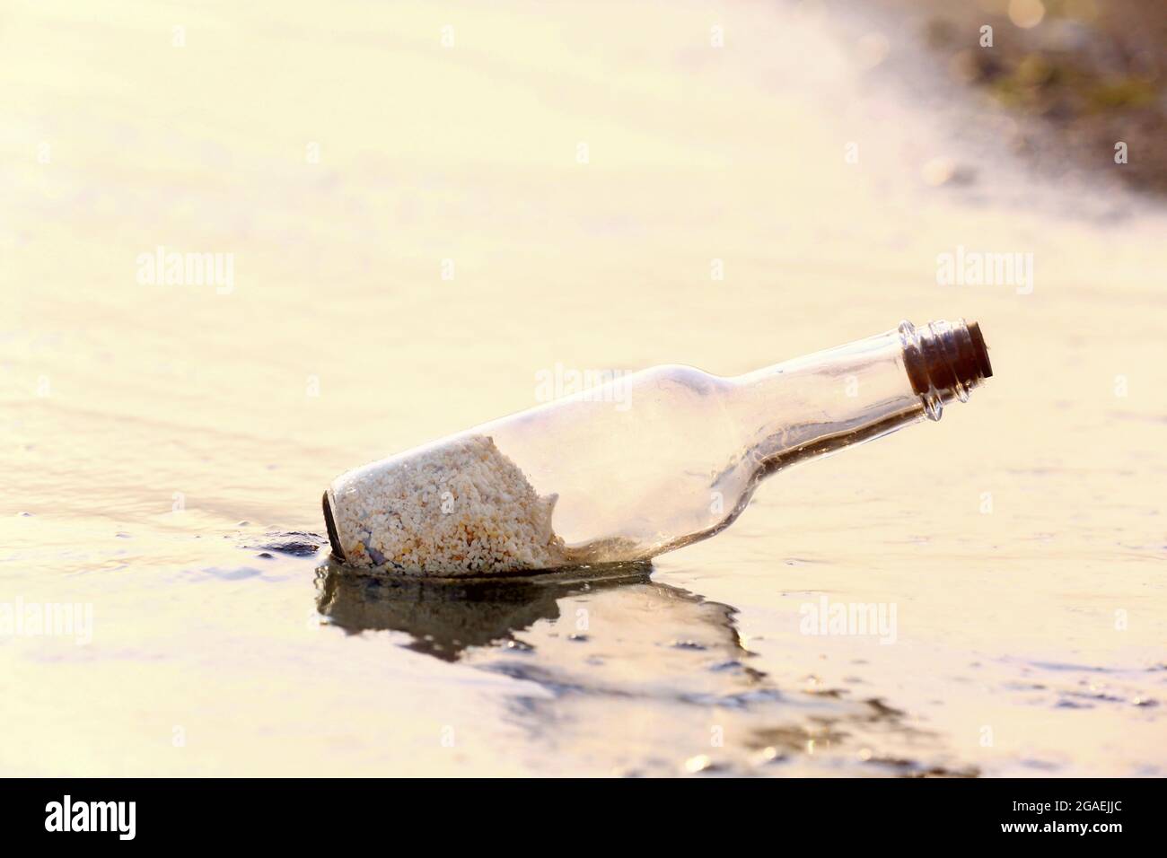 Glass bottle with sand inside on the beach Stock Photo