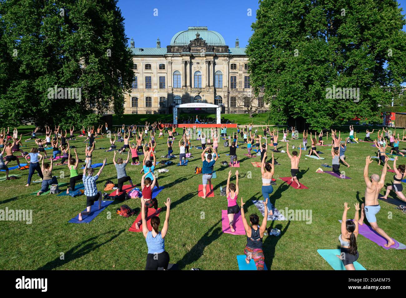 Dresden, Germany. 30th July, 2021. Participants do exercises on a lawn in the evening during a yoga class at the 'Palais Summer' in front of the Japanese Palace. Credit: Robert Michael/dpa-Zentralbild/ZB/dpa/Alamy Live News Stock Photo