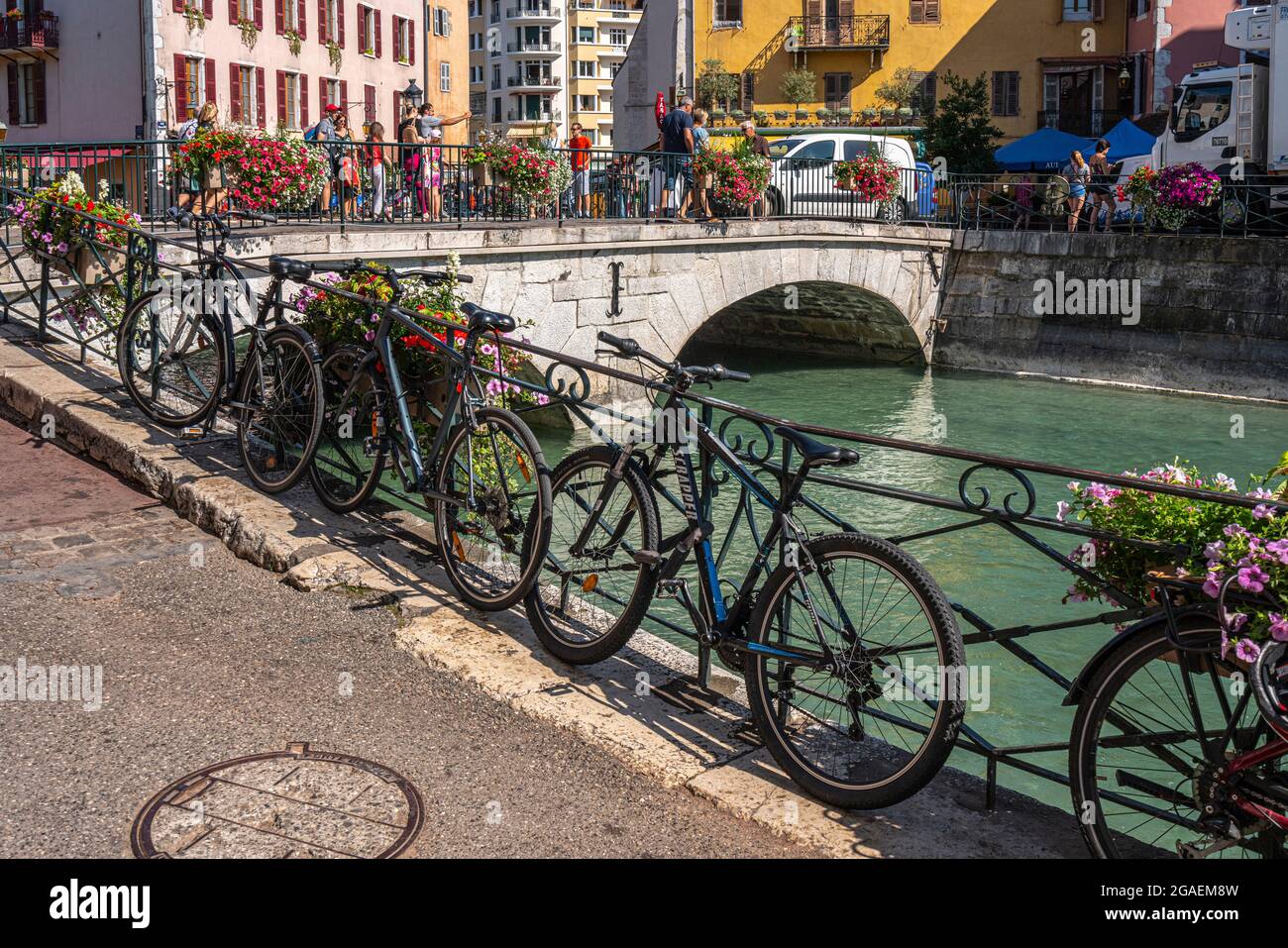 Bicycles parked near the Pont du Perriere in Annecy. Tourists stroll on the bridge visiting the city. Savoie department, France Stock Photo