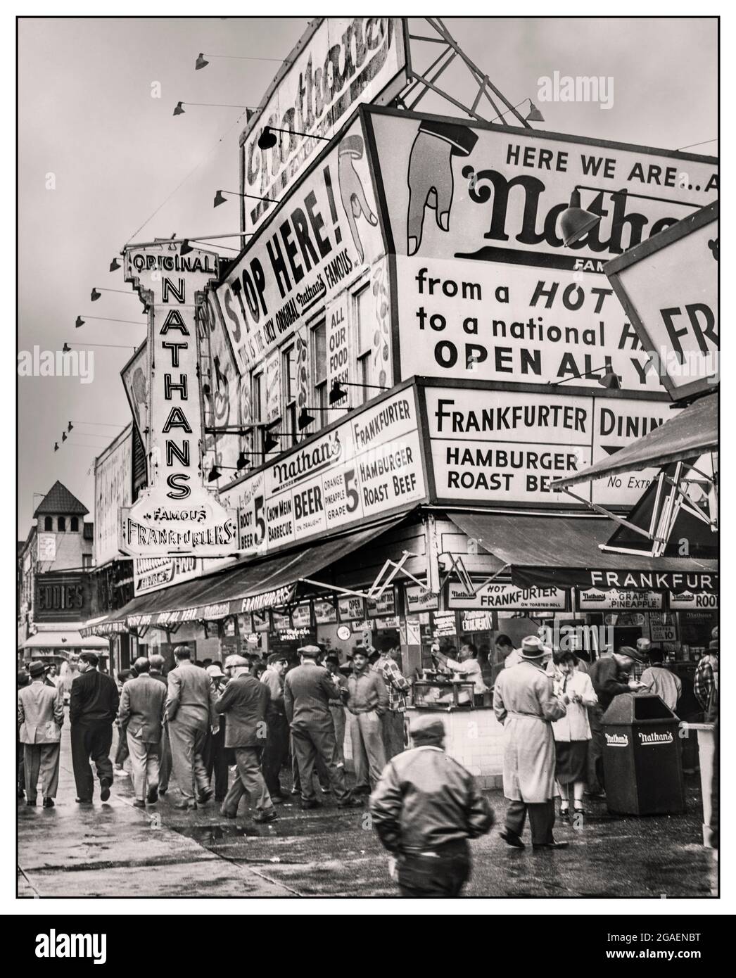 America Fast Food 1950's Stall Stand Nathan's Hot Dogs from boardwalk 1950's - showing a crowded street corner with customers ordering and eating from Nathan's food stand. World Telegram & Sun photo by Al Ravenna.'Nathan's on a rainy Monday morning still draws a frankfurter - bruncheon crowd, Coney Island.' USA 1954 Stock Photo