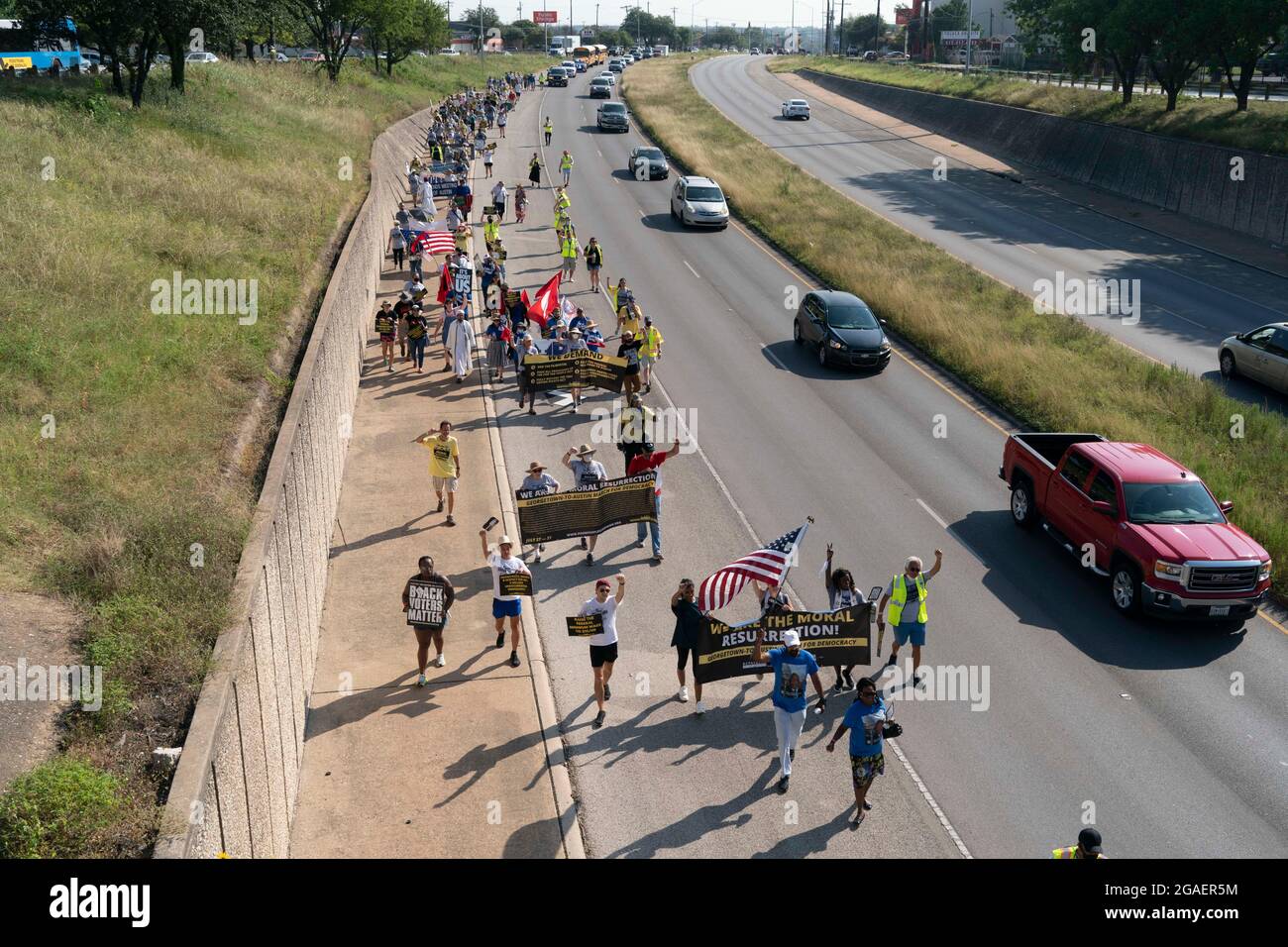 Austin, Texas USA, July 30, 2021: Voting rights activists march along an interstate highway frontage road toward the Texas Capitol from north Austin on the third day of a 30-mile journey protesting Republican efforts to suppress votes nationwide and in Texas. Shifts of marchers trade off in an effort to combat oppressive Texas heat. Credit: Bob Daemmrich/Alamy Live News Stock Photo