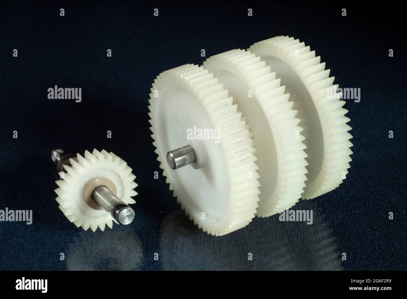 A white plastic gear on a table with a reflection. Spare parts on a black background Stock Photo