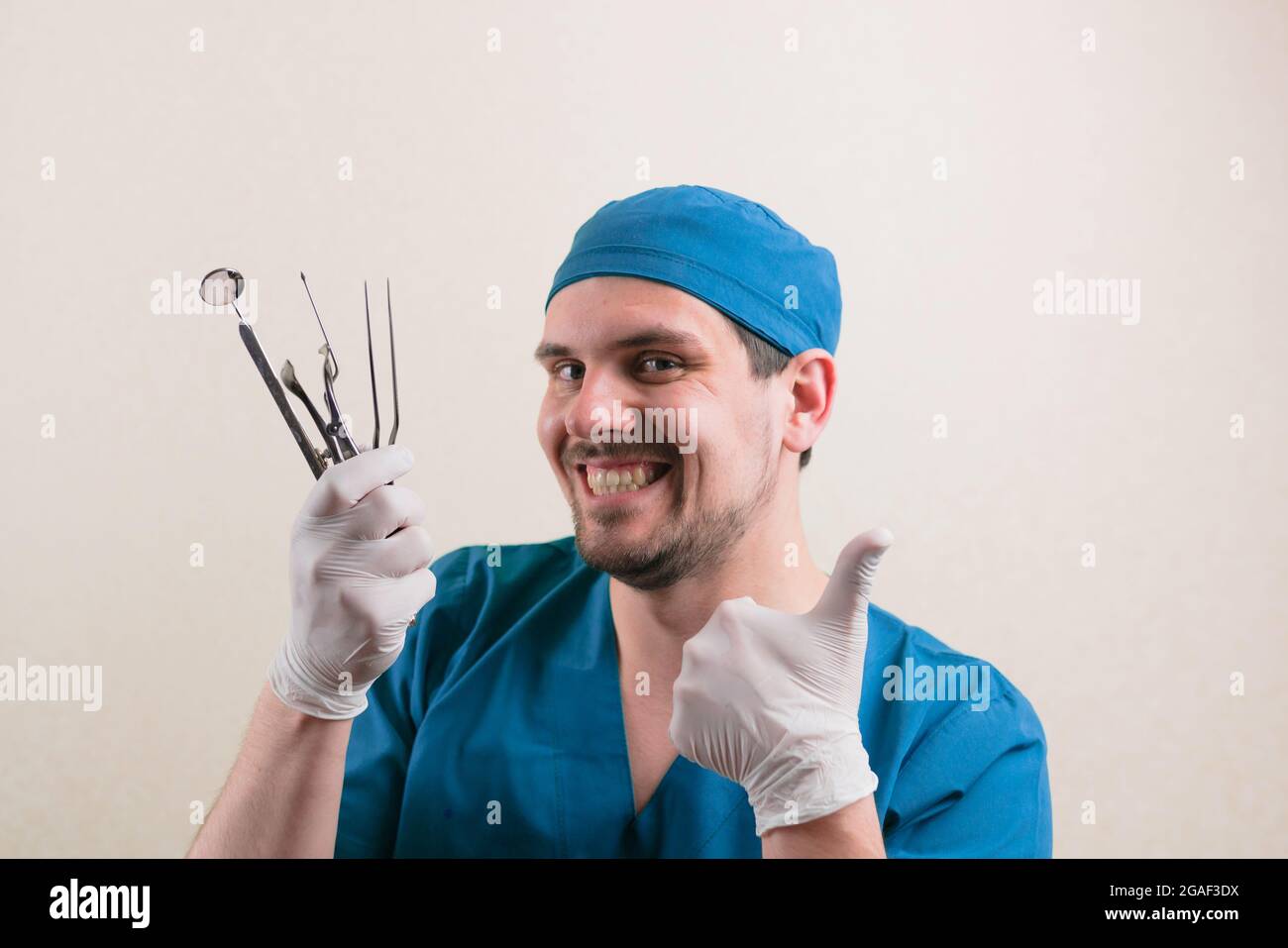 Young smiling doctor with medical instruments in his hand and thumb up