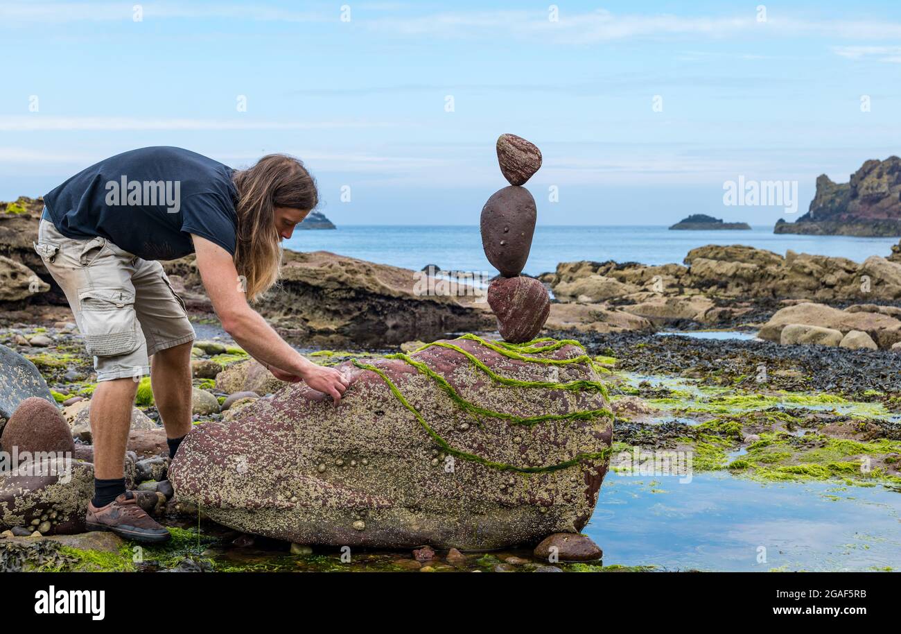 Jon Foreman, land artist, creates a stone balance on the beach at Dunbar, East Lothian, Scotland, UK Stock Photo