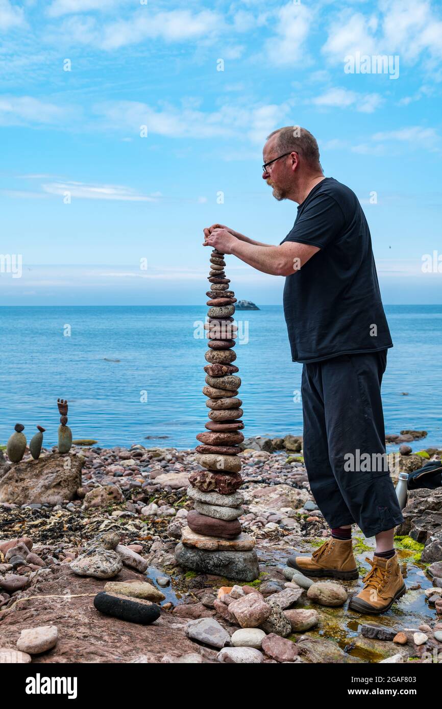 Neil Andrews stacks stones in a tower in the European Stone Stacking Championship on the beach, Dunbar, East Lothian, Scotland, UK Stock Photo