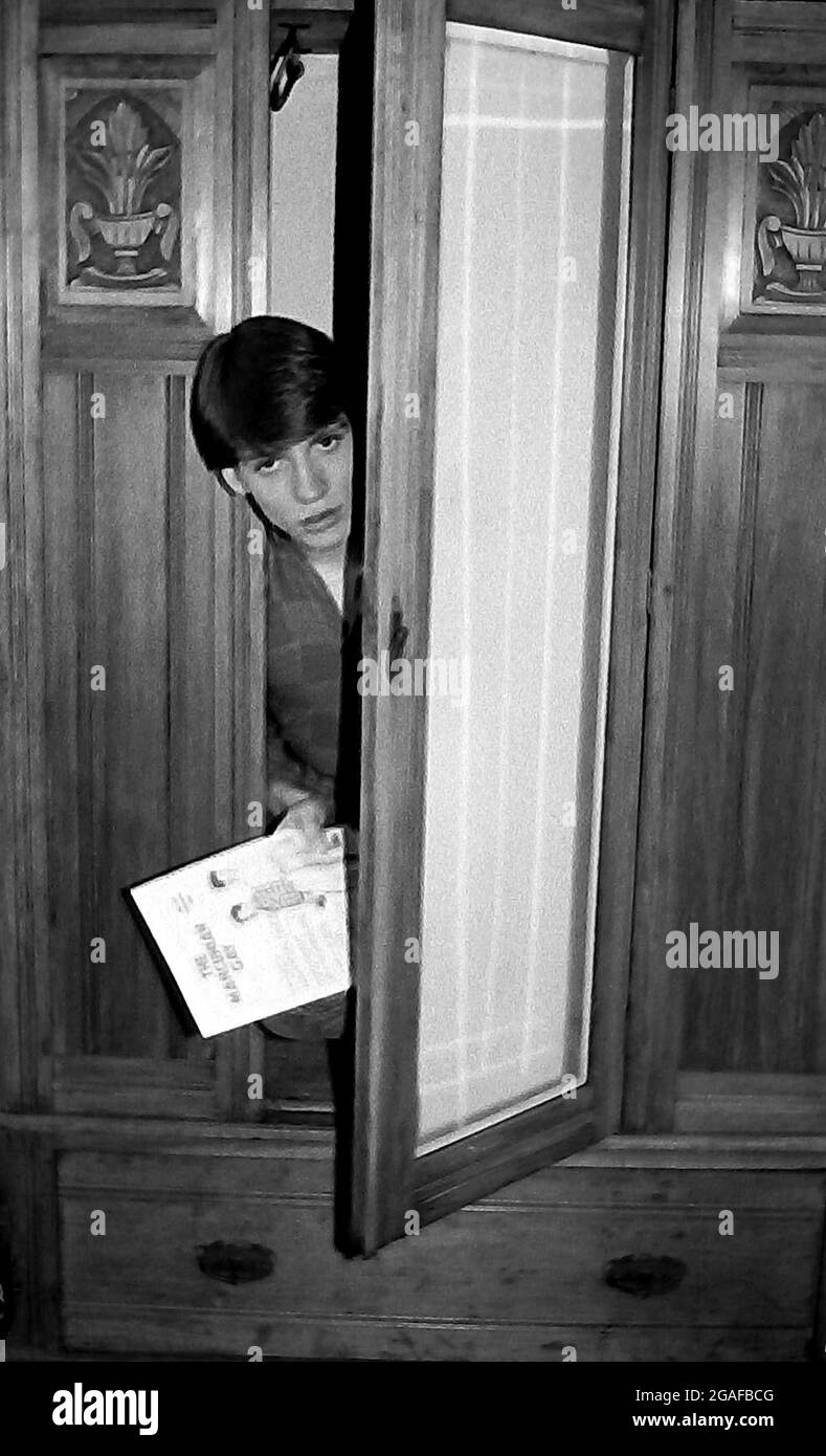 Young gay man comes out is the theme, with an 18 year old man emerging from an old wardrobe or closet. The model was Michael Higginson who later changed his name to Michael Waller. Part of a series taken for Mancunian Gay Magazine in 1984. The model is holding a copy of Mancunian Gay. Stock Photo