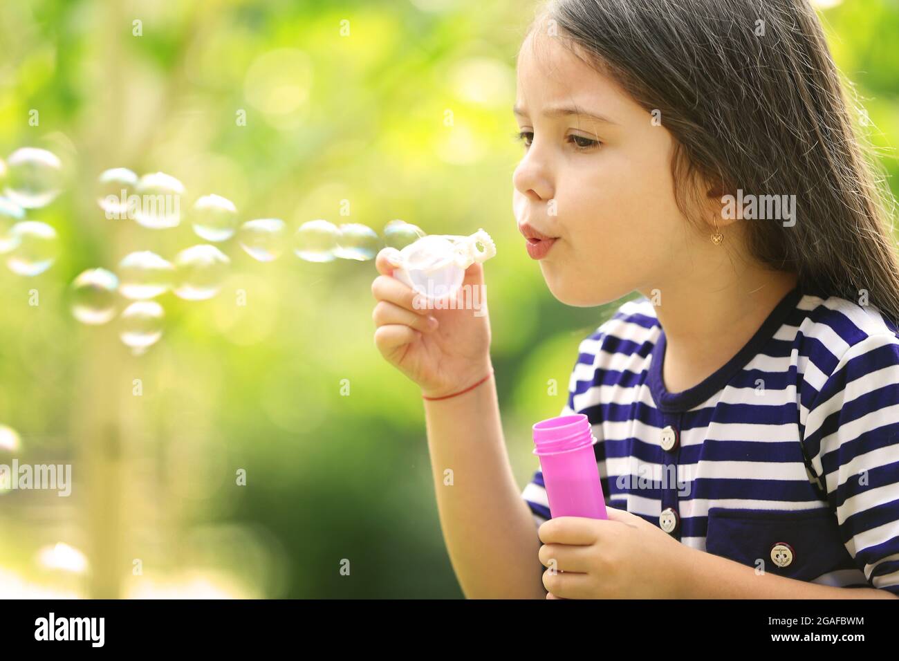 Happy little girl with bubbles in the park Stock Photo - Alamy