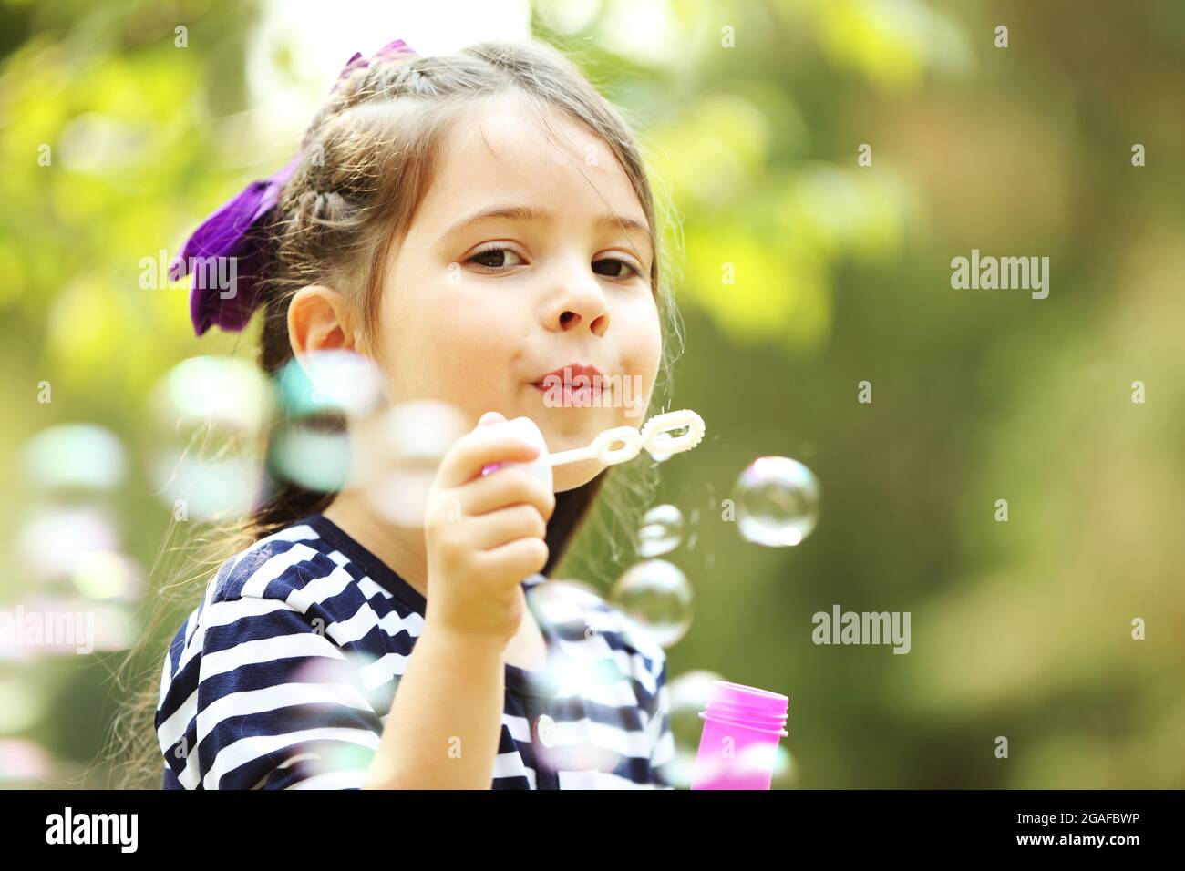 Happy little girl with bubbles in the park Stock Photo - Alamy