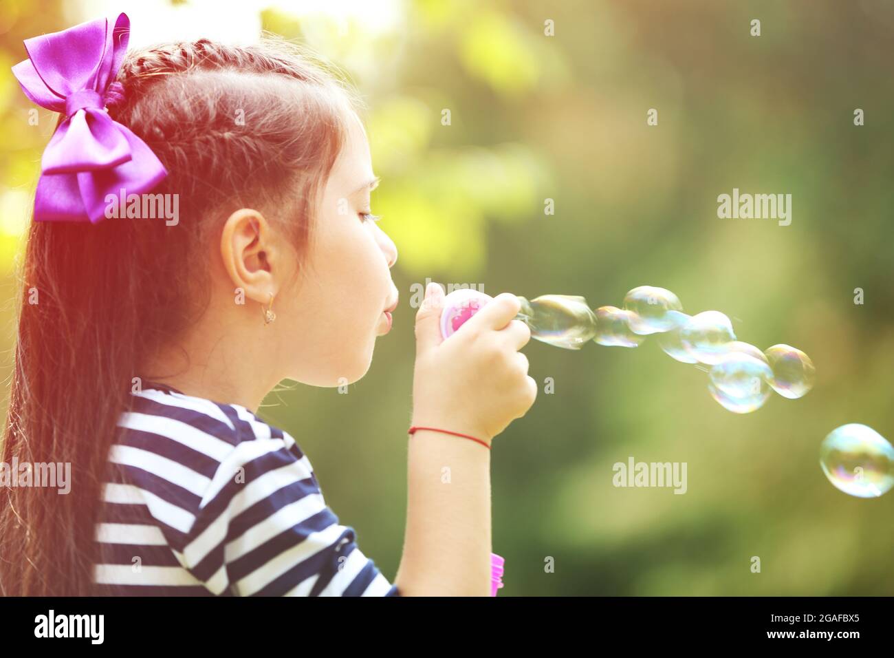 Happy little girl with bubbles in the park Stock Photo - Alamy